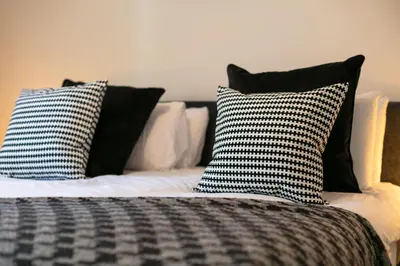 a bed with black and white pillows on it at Elliot Suite No7 - Donnini Apartments in Ayr