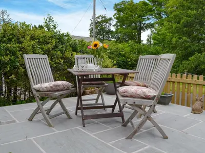 two chairs and a wooden table with flowers on a patio at Penfold in Dockray