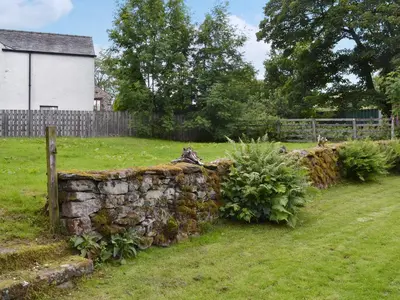 a stone wall in a field next to a house at Penfold in Dockray