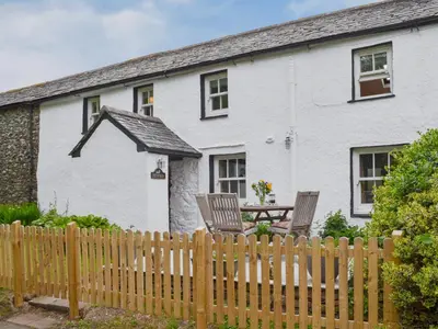 a white house with two chairs and a wooden fence at Penfold in Dockray