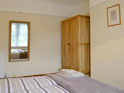a bedroom with a bed with a mirror and a cabinet at The Beeches in Bassenthwaite
