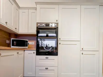 a kitchen with white cabinets and an oven at The Beeches in Bassenthwaite