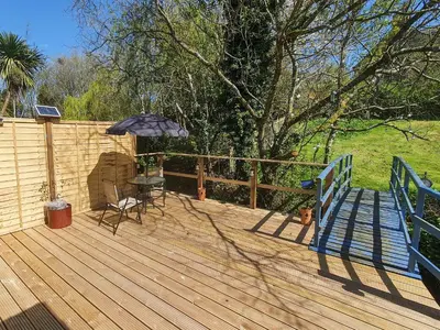 a wooden deck with a table and an umbrella at Burnside in Torthorwald