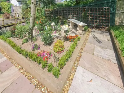 a garden with flowers and a bench on a patio at Burnside in Torthorwald