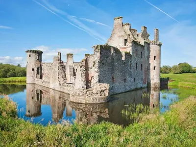 a castle in the middle of a body of water at Burnside in Torthorwald