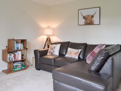 a living room with a leather couch and a book shelf at 6 Elm Court in Keswick