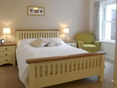 a bedroom with a bed and a chair and a window at 6 Elm Court in Keswick