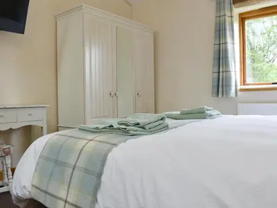 a bedroom with a white bed with towels on it at Wyndham Cottage in Dean