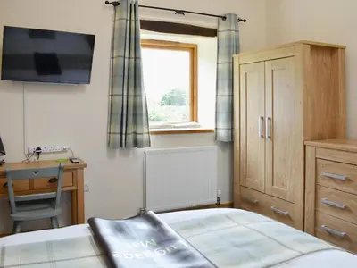 a bedroom with a bed and a desk and a window at Wyndham Cottage in Dean