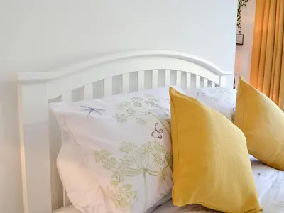 a white bed with yellow pillows on it at 3 Old Posting Stables in Gatehouse of Fleet