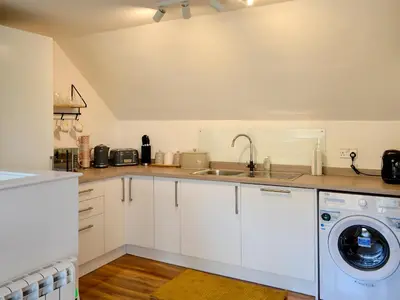 a kitchen with white cabinets and a washer and dryer at 3 Old Posting Stables in Gatehouse of Fleet