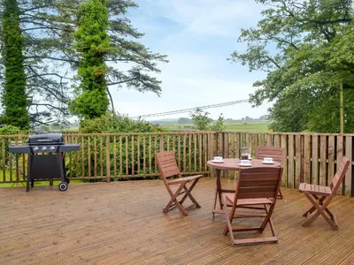 a patio with a table and chairs and a grill at The Soup Kitchen in Borgue