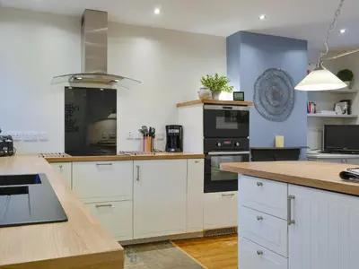 a kitchen with white cabinets and black appliances at Riverholme in Bassenthwaite
