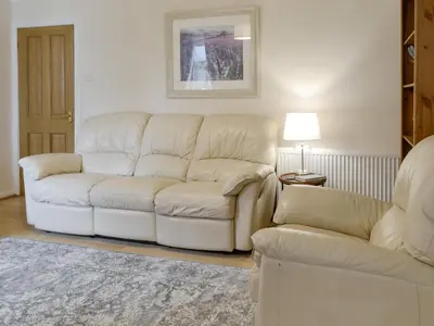 a living room with a white couch and a chair at Buckle House in Gatehouse of Fleet
