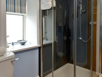 a shower with a glass door in a bathroom at Buckle House in Gatehouse of Fleet