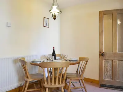 a dining room with a table with chairs and a bottle of wine at Swallows Return in Whitehaven