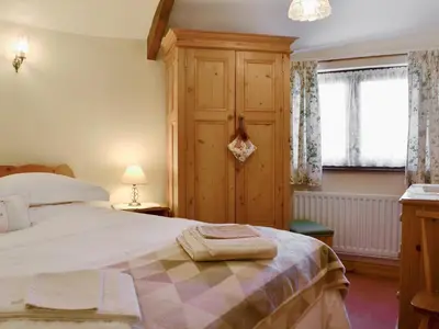 a bedroom with a bed and a wooden cabinet at Swallows Return in Whitehaven