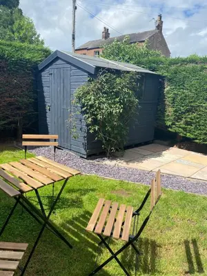 a picnic table and two benches in a yard with a shed at The Bothey in Brampton