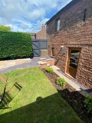 a backyard with a brick building and a lawn at The Bothey in Brampton