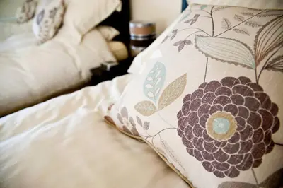 a bed with a pillow with a flower on it at Bamflatt Farm Bed & Breakfast in Strathaven