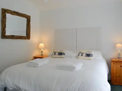 a bedroom with a white bed with a mirror at Shore Cottage - Uk12524 in Garlieston