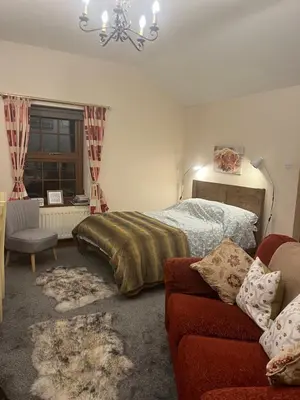 a bedroom with a bed and a couch and a chandelier at Stybeck Farm in Thirlmere