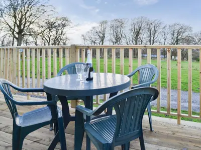 a table with two chairs and a bottle of wine at Robin's Lodge in Westward