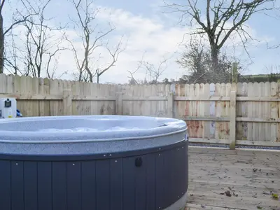 a hot tub in a yard next to a wooden fence at Robin's Lodge in Westward