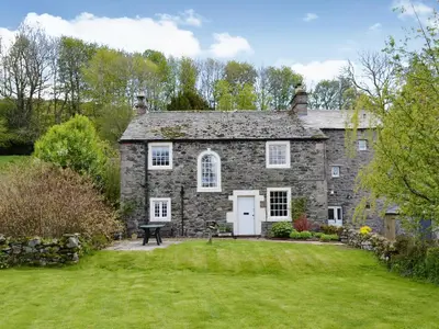 an old stone house with a grass yard at High Birch Close in Patterdale