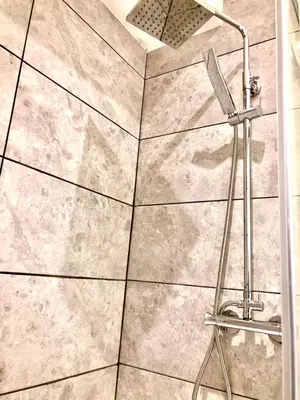 a shower in a bathroom with a tile floor at Maryport House in Maryport
