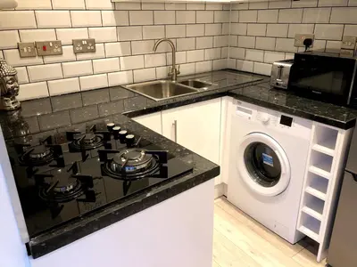 a kitchen with a stove top oven next to a washing machine at Maryport House in Maryport
