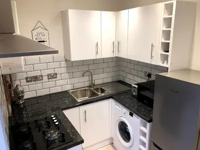 a kitchen with white cabinets and a sink and a dishwasher at Maryport House in Maryport