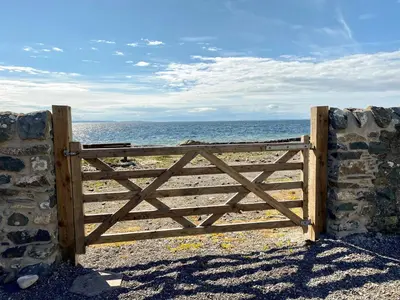 a wooden gate in front of the ocean at Saltlife Cottage in Port William