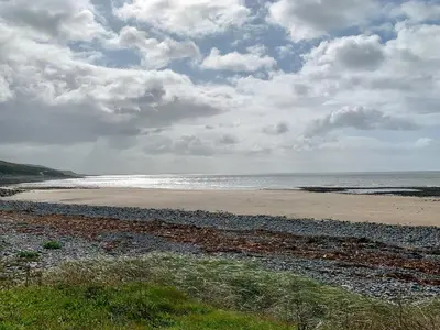 a beach with a cloudy sky and the ocean at Saltlife Cottage in Port William