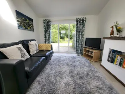 a living room with a black leather couch and a tv at Juniper HAYLOFT Grasmere in Ambleside