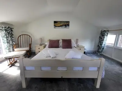 a bedroom with a large white bed and a chair at Juniper HAYLOFT Grasmere in Ambleside