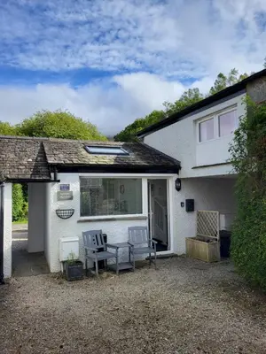 a white house with two chairs and a table at Juniper HAYLOFT Grasmere in Ambleside