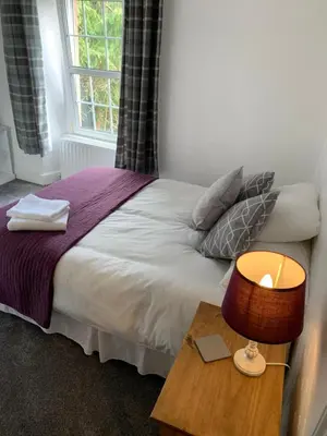 a bedroom with a bed and a table with a lamp at DOVENBY SHIP in Tallentire