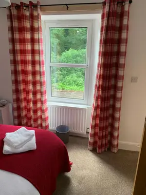 a bedroom with a red bed and a window at DOVENBY SHIP in Tallentire