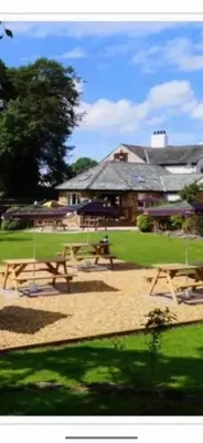 a park with picnic tables in front of a building at DOVENBY SHIP in Tallentire