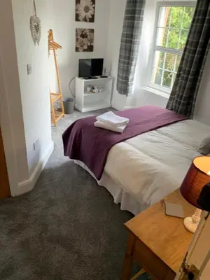 a bedroom with a bed with a purple blanket and a window at DOVENBY SHIP in Tallentire