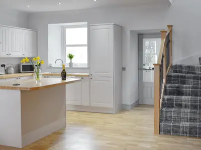 a kitchen with white cabinets and a counter top at The School House in New Luce