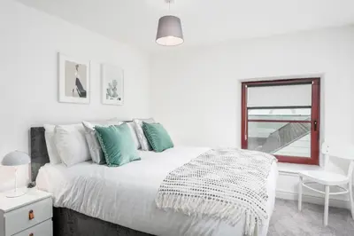 a white bedroom with a bed and a window at Granary Suite No22 - Donnini Apartments in Ayr