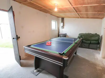 a ping pong table in a room with a pool at Meadowbank in Girvan
