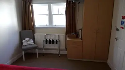 a bedroom with a window and a chair and a dresser at Star Hotel in Kirkcudbright