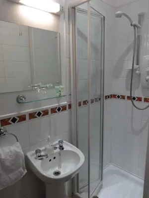 a white bathroom with a sink and a shower at Dumfries Villa in Dumfries