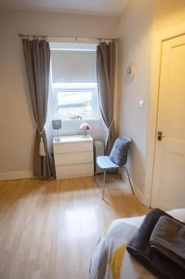 a bedroom with a bed and a window and a chair at Sandgate 2-Bed Apartment in Ayr central location in Ayr