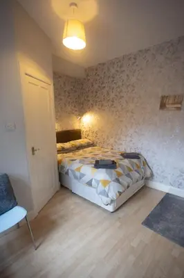 a bedroom with a bed and a chair in it at Sandgate 2-Bed Apartment in Ayr central location in Ayr