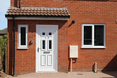 a brick building with a white door and two windows at Carvetii - Phoenix House - Near Hospital, max 8 ppl in Carlisle