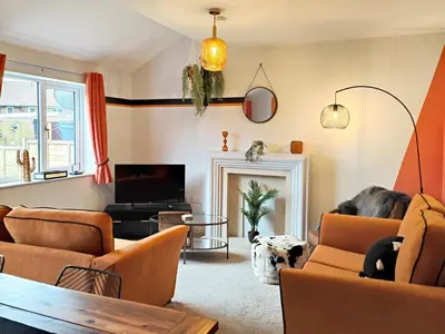 a living room with orange furniture and a tv at Carvetii - Phoenix House - Near Hospital, max 8 ppl in Carlisle